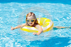 Child in swimming pool on ring toy. Kids swim