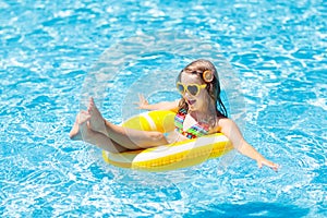 Child in swimming pool on ring toy. Kids swim