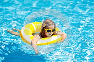 Child in swimming pool on ring toy. Kids swim