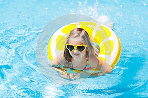 Child in swimming pool on ring toy. Kids swim