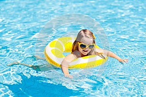 Child in swimming pool on ring toy. Kids swim