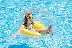 Child in swimming pool on ring toy. Kids swim