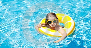 Child in swimming pool on ring toy. Kids swim