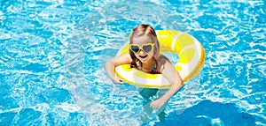 Child in swimming pool on ring toy. Kids swim