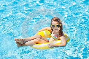 Child in swimming pool on ring toy. Kids swim