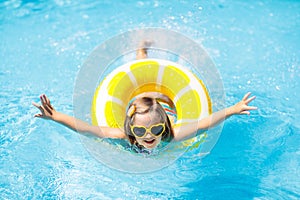 Child in swimming pool on ring toy. Kids swim photo