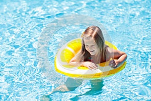 Child in swimming pool on ring toy. Kids swim