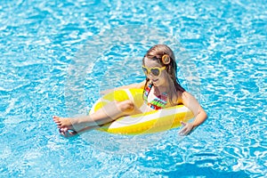 Child in swimming pool on ring toy. Kids swim