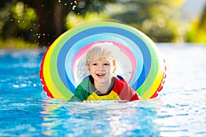 Child in swimming pool on toy ring. Kids swim