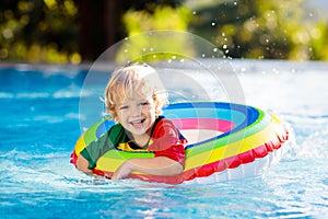 Child in swimming pool on toy ring. Kids swim