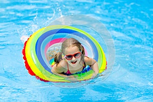 Child in swimming pool on toy ring. Kids swim