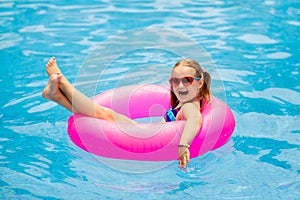 Child in swimming pool on toy ring. Kids swim