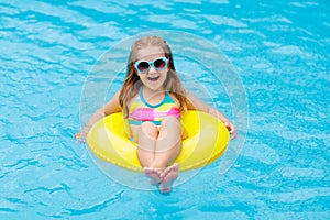 Child in swimming pool on toy ring. Kids swim