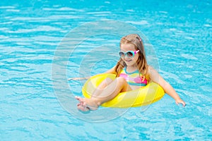 Child in swimming pool on toy ring. Kids swim