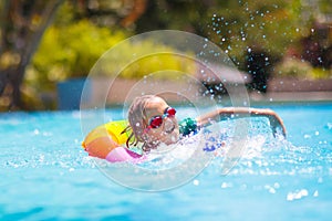 Child in swimming pool on toy ring. Kids swim