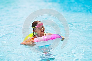 Child in swimming pool on toy ring. Kids swim