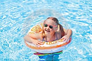 Child in swimming pool on toy ring. Kids swim