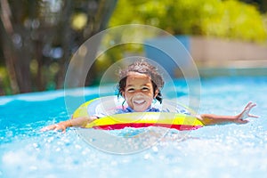 Child in swimming pool on toy ring. Kids swim