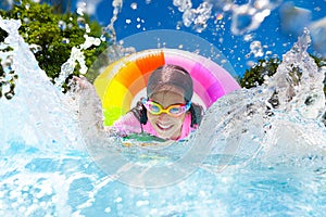 Child in swimming pool on toy ring. Kids swim