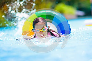 Child in swimming pool on toy ring. Kids swim