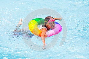 Child in swimming pool on toy ring. Kids swim