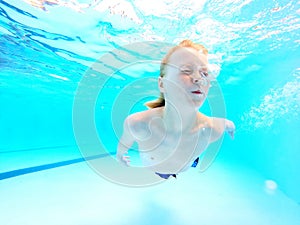 Child Swimming Under Water in Pool