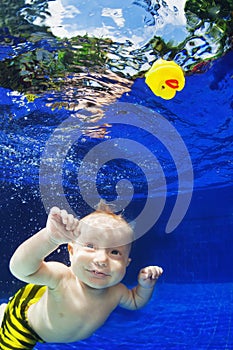 Child swimming underwater in blue pool for yellow toy