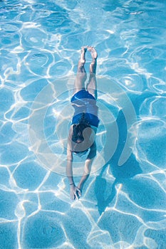 Child swimming underwater in an outdoor pool