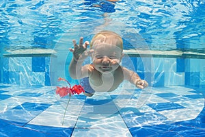 Child swimming underwater for a red flower in the pool