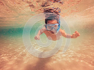 Child swimming underwater with swim mask