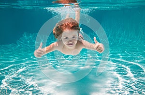 Child swimming underwater with thumbs up. Underwater kid swim under water. Child boy swimming and diving underwater in