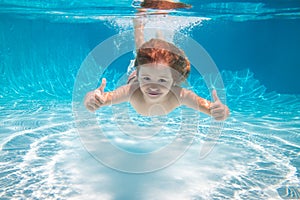 Child swimming underwater with thumbs up. Underwater kid swim under water. Child boy swimming and diving underwater in