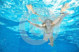 Child swims in pool underwater, girl has fun under water, active kid sport on vacation
