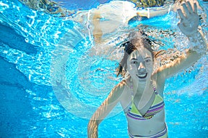 Child swims in pool underwater, girl has fun in water