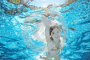 Child swims in pool underwater, girl has fun in water