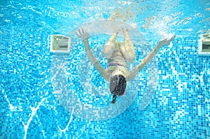 Child swims in pool underwater, girl has fun in water