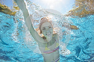 Child swims in pool underwater, girl has fun in water