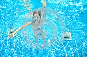 Child swims in pool underwater, girl has fun in water