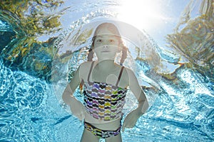 Child swims in pool underwater, girl has fun in water