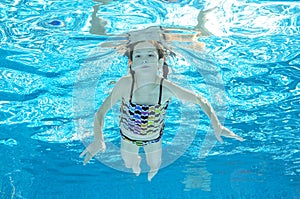 Child swims in pool underwater, girl has fun in water