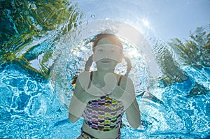 Child swims in pool underwater, girl has fun in water