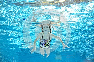Child swims in pool underwater, girl has fun in water