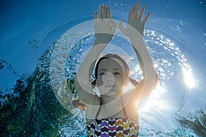 Child swims in pool underwater, girl has fun in water