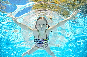 Child swims in pool underwater, girl has fun in water