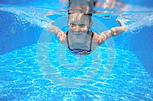 Child swims in pool underwater, girl has fun in water