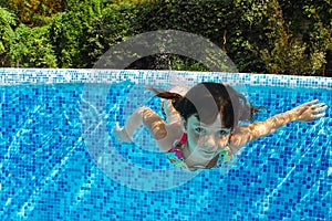 Child swims in pool underwater, happy active girl dives and has fun under water, kid fitness and sport