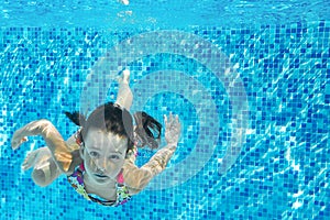 Child swims in pool underwater, happy active girl dives and has fun under water, kid fitness and sport