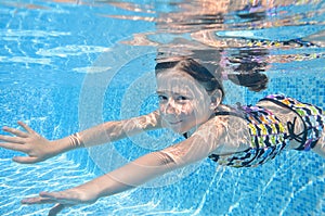 Child swims in pool underwater, happy girl dives and has fun under water, kid fitness and sport on family vacation