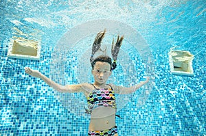 Child swims in pool underwater, happy active girl dives and has fun under water, kid sport