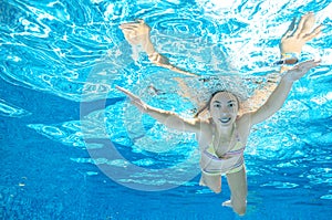 Child swims in pool underwater, happy active girl dives and has fun under water, kid sport